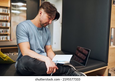 Student learning in university library. Young man reading his notes. Man using computer to learn. Focused student studying for college exams. Back to school - Powered by Shutterstock