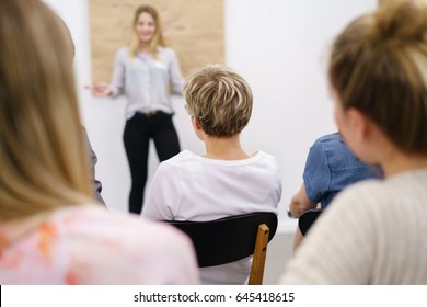 Student Listening To A Lecture Or Presentation In Class Seated In The Front Row Of The Audience With Selective Focus To The Back Of The Head