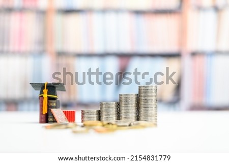 Student loan and financial decision-making, financial literacy concept : Graduation cap, books and coins on a table. Financial literacy is the ability to understand and make use of financial skills.