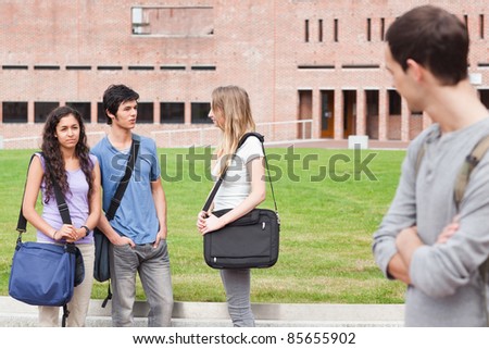 Student looking at one of his classmates talking outside a building