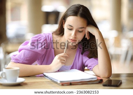 Student memorizing notes sitting in a restaurant terrace