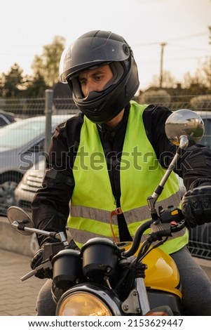 A student of a motorcycle school in a training vest is having a driving lesson. Motorcyclist in a helmet and gear. Riding a motorcycle. Motorcycle power.