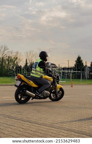 A student of a motorcycle school in a training vest is having a driving lesson. Motorcyclist in a helmet and gear. Riding a motorcycle. Motorcycle power.