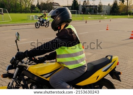 A student of a motorcycle school in a training vest goes around traffic cones. Driving lesson. Getting a motorcycle license.