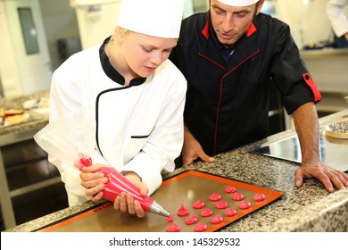 Student in pastry making cookies with help of teacher