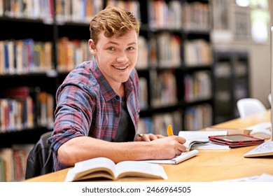 Student, portrait and notebook in library for study, education and university quiz with pen on table. Man, happy and books on school campus for college exam, research and learning with scholarship