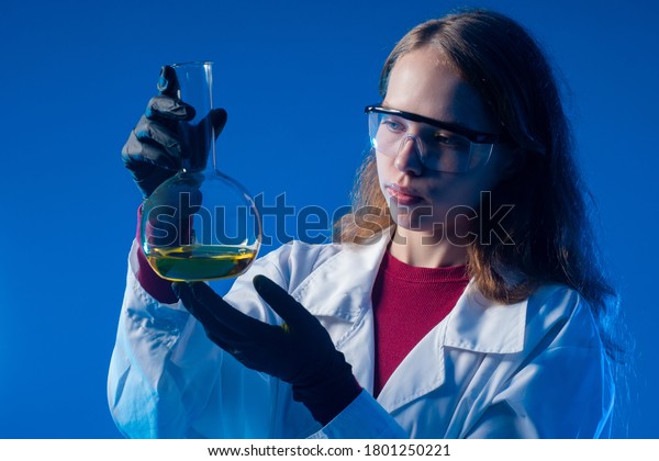 A student in\
practical classes in chemistry. The girl is holding a flask with a\
yellow chemical liquid. Demonstration of chemical experiments at\
school. Chemical research.