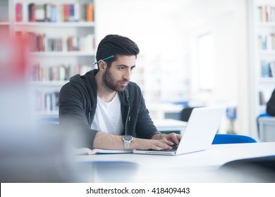 Student Preparing Exam And Learning Lessons In School Library, Making Research On Laptop And Browse Internet