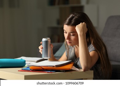 Student preparing exam memorizing notes holding and energy drink in the night at home