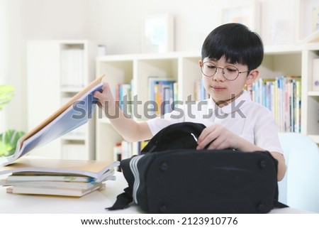 A student preparing to go to school with a backpack or a student preparing homework by organizing books after school
