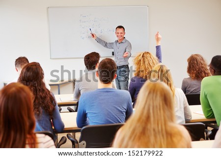 Student raising hand in school class and getting called by teacher