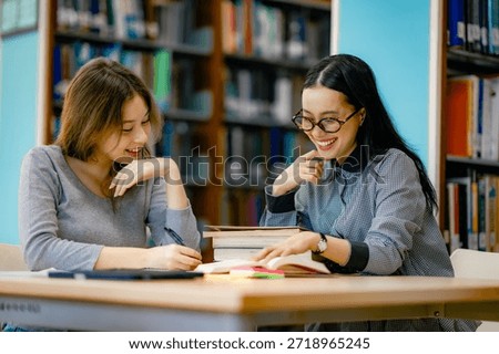 Student receiving help with homework at library table using open books guided learning education support. 