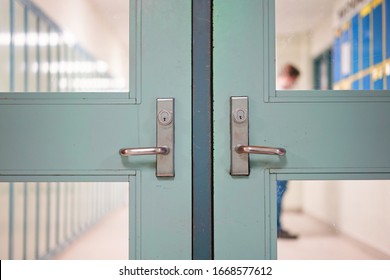 Student Returning Back To School In Person. School Reopening Following Social Distancing Rule After Covid-19 Pandemic Lockdown. Door And Handle See Through Lockers And Student Standing At Background.