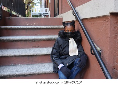 Student Sitting On City Brownstone Steps Wearing Black Face Mask