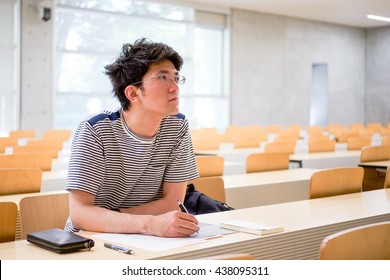 Student Sitting Reading A Book And Taking Notes In Lecture Hall