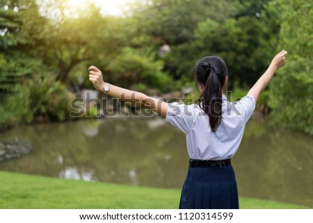 ํYoung student standing at the park , refresh after exams being finished.Garden background.