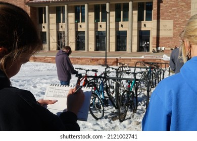 A Student Stands Outside Sketching A Building On A Pad Of Paper For An Art Class