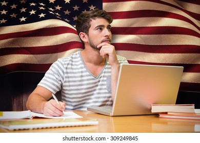 Student Studying In The Library With Laptop Against Composite Image Of Digitally Generated United States National Flag