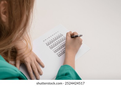 A student takes a written exam, fills out a multiple choice test, and checks the boxes with answers. - Powered by Shutterstock