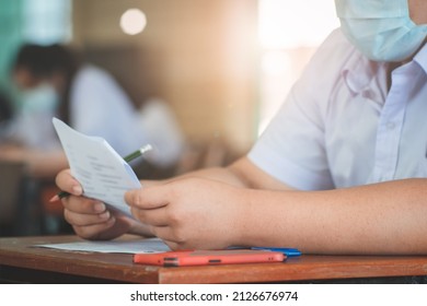 Student Taking Exam While Wearing Face Mask Due To Coronavirus Emergency. Young Woman Sitting In Class With Wearing Surgical Mask Due To Covid-19 Pandemic