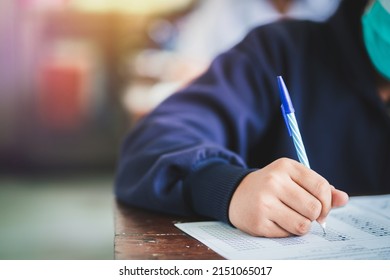 Student Taking Exam While Wearing Face Mask Due To Coronavirus Emergency. Young Woman Sitting In Class With Wearing Surgical Mask Due To Covid-19 Pandemic