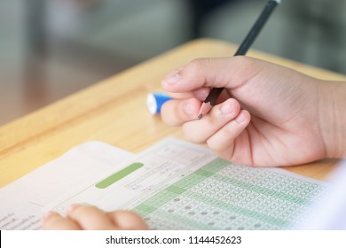 Student Taking Exams, Writing Examination On Paper Answer Sheet Optical Form Of Standardized Test On Desk Doing Final Exam In Classroom, Examination Sitting On Row Chair In School.