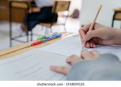 Student Taking Notes Lecture In High School Or University With Holding Pencil Writing On Paperwork Sheet And Taking Final Exam In Examination Classroom