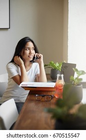 Student Talking On Phone In Cafe Or Coworking Hub Drinking Lemonade Using Laptop