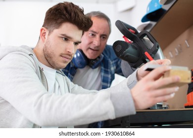 Student And Teacher In Carpentry Class Using Circular Saw