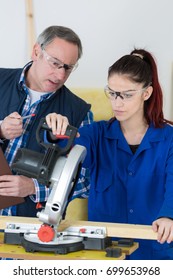 Student And Teacher In Carpentry Class Using Circular Saw