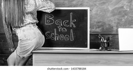 Student Teacher Mini Skirt Sexy Buttocks Sit Table Blackboard Inscription Back To School. Girl Denim Skirt Breaking School Clothing Rules. School Dress Code. Back And Buttocks Student Near Chalkboard.