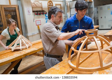 Student And Teacher Standing In A Woodwork Class And Working On A Structure