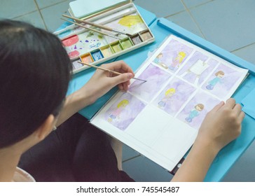 Student Teenage Girl Hands Drawing Cartoon In Watercolor About Her Teen Life On Blue Table.