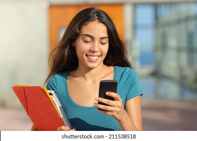 Student Teenager Girl Walking While Looking Her Smart Phone With The College Door In The Background               