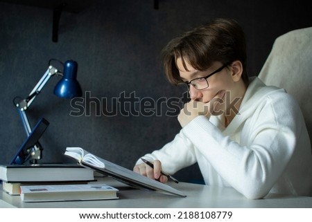 Student - a teenager in glasses carefully reads the phone