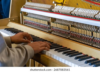 Student testing piano during practical class, checking keyboard and hammer mechanism operation in educational music or piano technology workshop environment