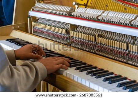 Student testing piano during practical class, checking keyboard and hammer mechanism operation in educational music or piano technology workshop environment