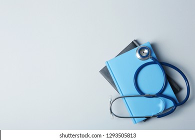 Student textbooks, stethoscope and space for text on grey background. Medical education