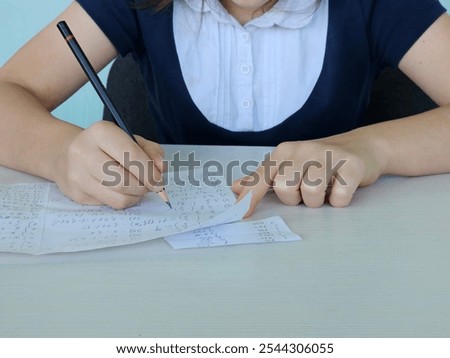 Student using formula math sheet to cheat on test. Hand of university student holding pencil doing math question in examination and cheating in test with answer piece of paper in hand.
