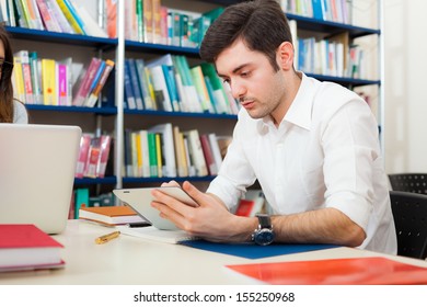 Student using his digital tablet in a library