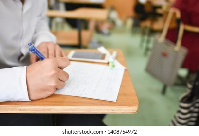 Student Using A Pen Writing Or Taking Lecture Notes In The Classroom; Education Concept Picture Or Photo Of Young Learner Doing Assignment In A Career Development Center Of The College Or University 