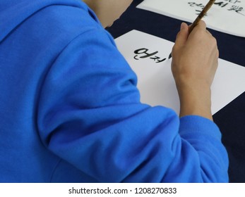 A student wearing blue clothes is writing hangul(Korean alphabet). translation : Always. - Shutterstock ID 1208270833