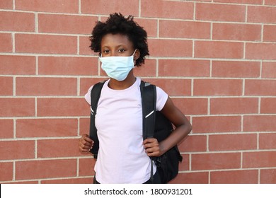 Student wearing surgical face mask and backpack outdoors