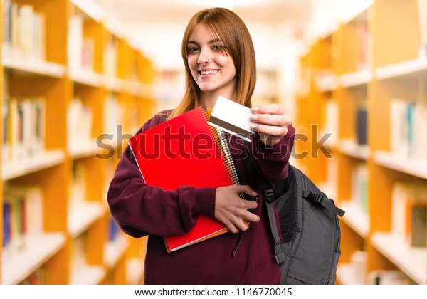 Student woman holding a credit card on\
unfocused background