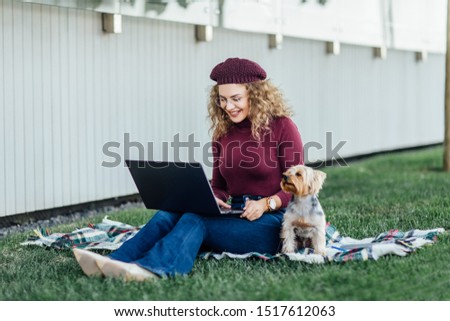 Student woman sitting on the blanket and have a picnic time with her Yorkshire terrier dog.