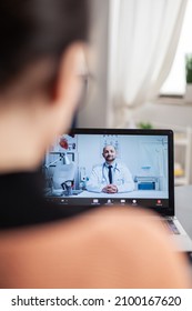 Student Working From Home Videocalling Doctor On Laptop. Over Shoulder View Of Freelancer In Online Medical Consultation Video Call. Physician Gives Health Advice On Webcam.