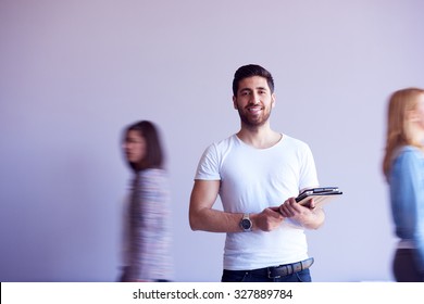 Student Working On Tablet Computer At University School Modern Interior, People Group Passing By In Background And Make Movement Trails