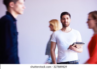 Student Working On Tablet Computer At University School Modern Interior, People Group Passing By In Background And Make Movement Trails