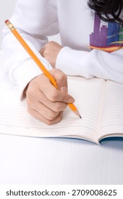 Student writes notes with a pencil in a notebook during a study session
