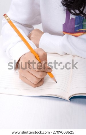 Student writes notes with a pencil in a notebook during a study session